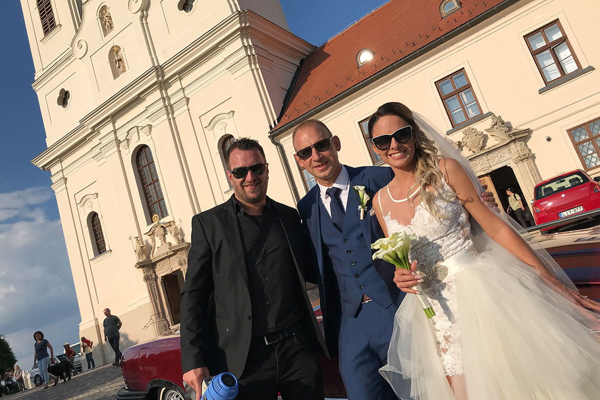 Kiss Levente ceremóniamester az ifjú párral egy barokk templom előtt